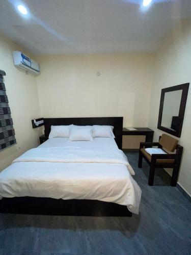a bedroom with a large white bed and a chair at Studio Room Apartment in Port Harcourt