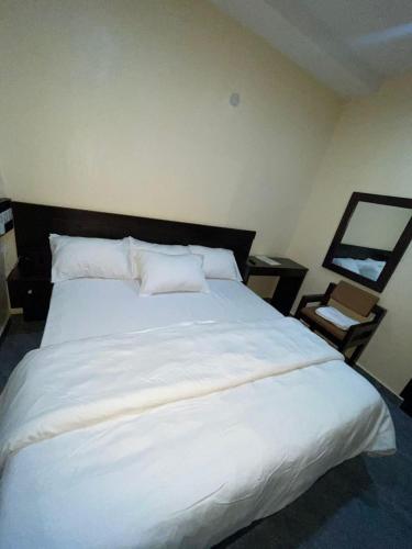 a large white bed in a room with a chair at Studio Room Apartment in Port Harcourt
