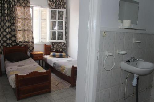 - une salle de bains avec lavabo et 2 lits dans une chambre dans l'établissement Hotel de la plage, à Bizerte