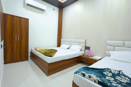 a bedroom with two beds and a wooden cabinet at Shiv Residency in Mathura