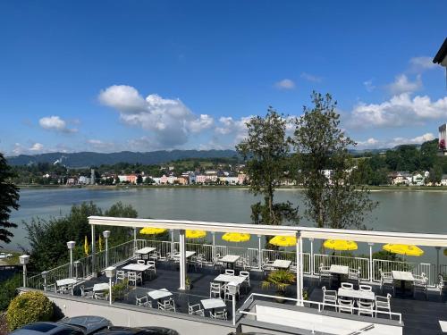a patio with tables and chairs and umbrellas next to a river at Hotel-Restaurant Faustschlössl in Feldkirchen an der Donau