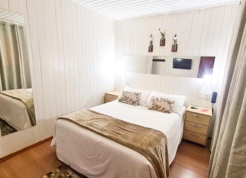 Dormitorio pequeño con cama y espejo en Pousada Mima en Gramado