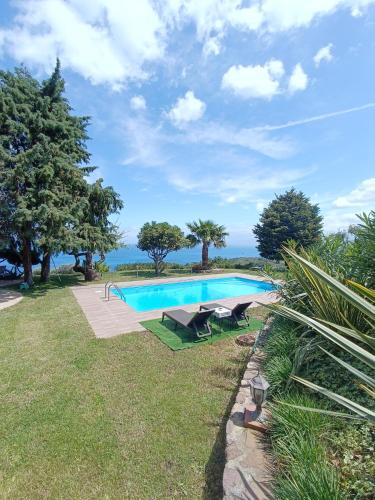 a swimming pool in a grassy area with trees and the ocean at LA Casa di Matilde in Gioiosa Marea