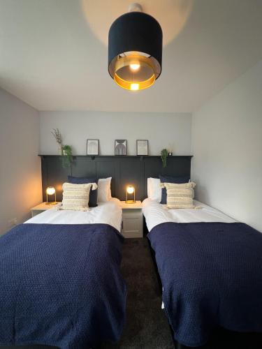 twee bedden in een kamer met blauwe lakens bij Campbells Crib in Kent