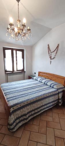 a large bed in a bedroom with a chandelier at ACERO ROSSO in Cortenova