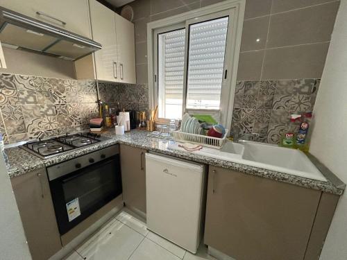 a small kitchen with a sink and a stove at Appartement haut standing a sousse in La Corniche