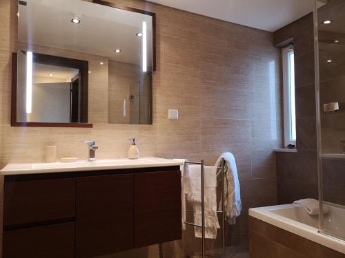 uma casa de banho com um lavatório, um espelho e uma banheira em luxury Plazza Sea view em Costa da Caparica