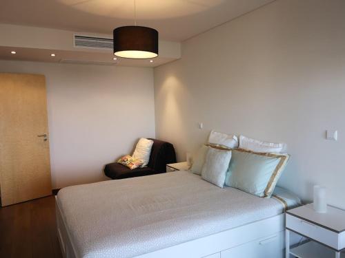 ein kleines Schlafzimmer mit einem Bett und einem Stuhl in der Unterkunft luxury Plazza Sea view in Costa da Caparica