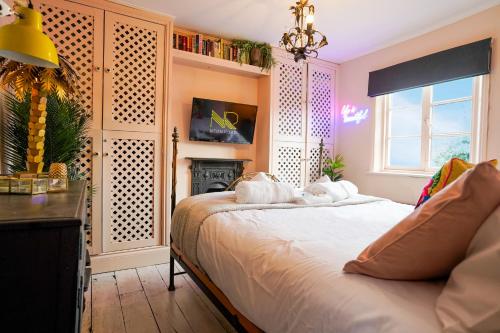 um quarto com uma cama branca e uma lareira em Cheltenham 3 Bedroom Cottage-Neon Wonderland-Town Centre-Parking-Sleeps 6 