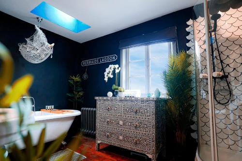 ein blaues Badezimmer mit einer Badewanne und einem Waschbecken in der Unterkunft Cheltenham 3 Bedroom Cottage-Neon Wonderland-Town Centre-Parking-Sleeps 6 
