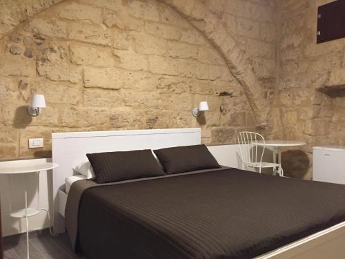 een slaapkamer met een bed en een stenen muur bij B&B 62 Marinai in Bari