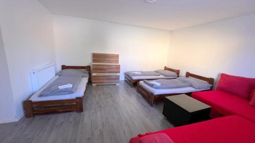 a room with three beds and a red couch at Apartmánový dom Most pri Bratislave in Senec