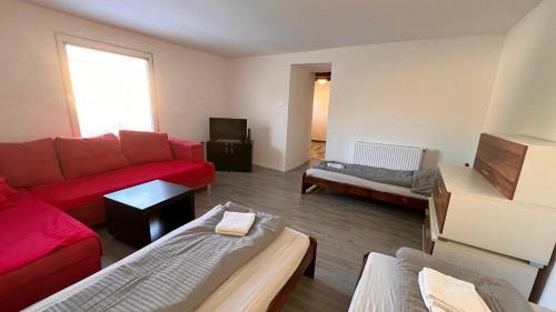 ein Wohnzimmer mit einem roten Sofa und einem TV in der Unterkunft Apartmánový dom Most pri Bratislave in Senec