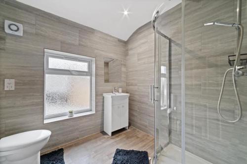 een badkamer met een douche, een toilet en een wastafel bij Perfectly Located 2-Bed w/ Free Private Parking in Peterborough