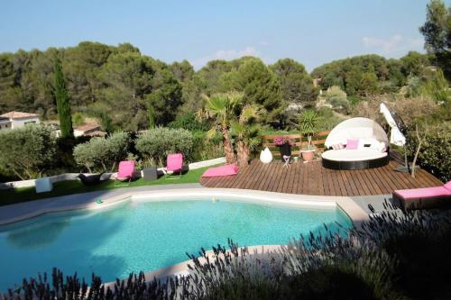 einen Pool mit rosa Stühlen und einem Pavillon in der Unterkunft Villa climatisée Aix en Provence grande piscine, boulodrome, vue in Ventabren