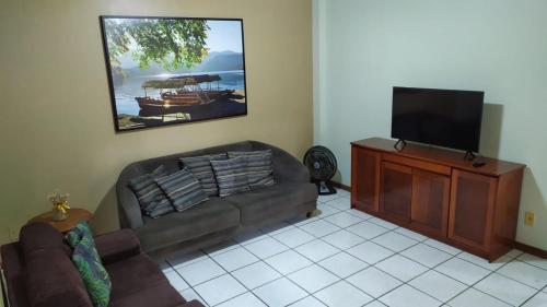 un salon avec un canapé et une télévision à écran plat dans l'établissement Apartamento na quadra do mar, à Itapema