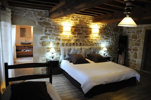 une chambre avec un lit et un mur en pierre dans l'établissement Escale en Charolais Brionnais, à Saint-Julien-de-Civry