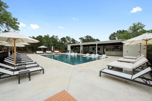 a swimming pool with lounge chairs and umbrellas at The Cedars Ranch in Wimberley