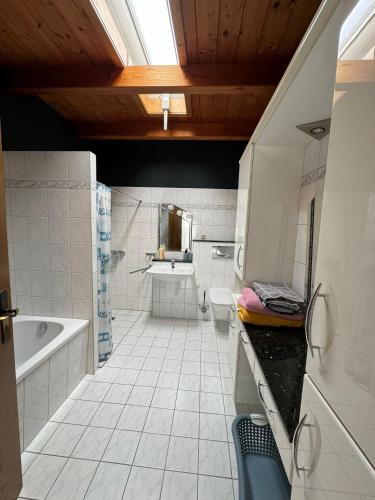 a white bathroom with a tub and a sink at Moderner Bungalow in Mönchengladbach in Mönchengladbach
