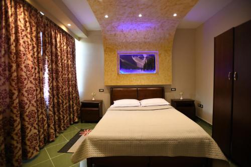 1 dormitorio con 1 cama y una pintura en la pared en Hotel Ago en Berat