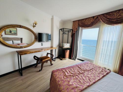 1 dormitorio con cama, espejo y ventana en Roxo Beach Hotel, en Erdemli