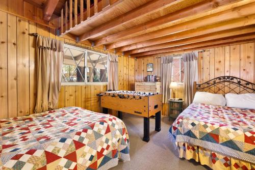 a bedroom with two beds and a wooden wall at Oriole cottage #621 in Big Bear Lake