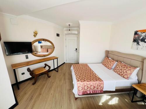 1 dormitorio con cama, espejo y escritorio en Roxo Beach Hotel, en Erdemli