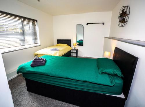 a bedroom with a green bed and a mirror at Libra House retreat, Caswell Bay in Swansea