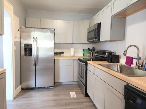 a kitchen with white cabinets and a stainless steel refrigerator at Dundee Escape in Charleston