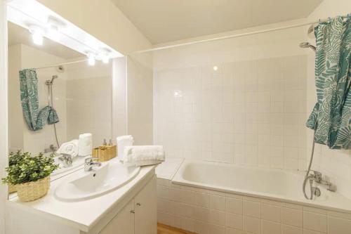 un bagno bianco con vasca, lavandino e vasca tubermott di Le Salmson - Studio proche gare a Laval