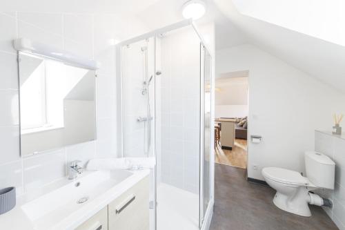 uma casa de banho branca com um chuveiro e um WC. em LE BALI - 10min à pied de la Gare em Laval
