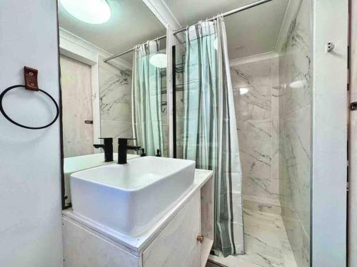 uma casa de banho com um lavatório e um chuveiro em Secure Stylish Off Grid Flatlet em Gqeberha