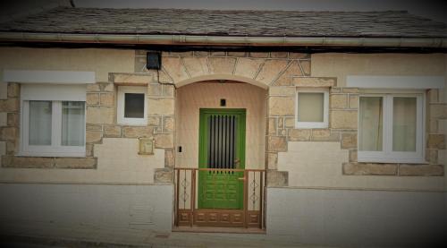 une porte verte sur une maison avec un balcon dans l'établissement Amodiño,casa alquiler vacacional, à Viveiro