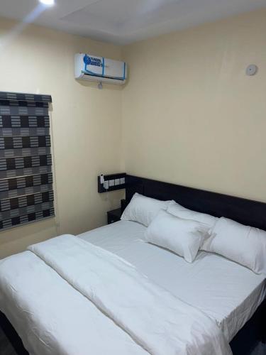 a bedroom with a large white bed with white pillows at Studio Room Apartment in Port Harcourt