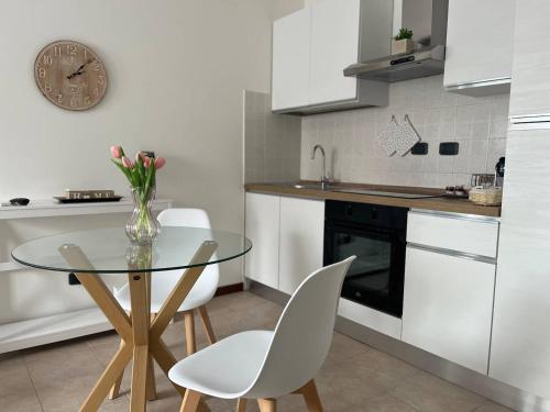 a kitchen with a glass table and white chairs at Perla Apartment Verona in Verona