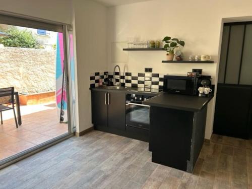 Il comprend une cuisine équipée d'une cuisinière et d'un comptoir avec un four micro-ondes. dans l'établissement A 150 m de la mer,terrasse 30m, Clim wifi parking, à Sausset-les-Pins