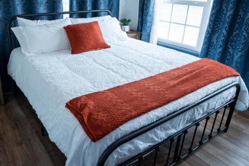 a bed with an orange and white blanket on it at Vasanoja Suite 102, Hyland Hotel in Palmer