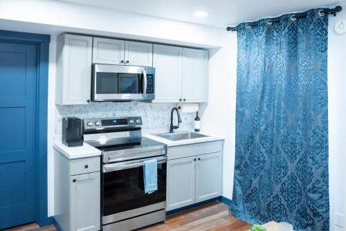 a kitchen with white cabinets and a sink and a microwave at Vasanoja Suite 102, Hyland Hotel in Palmer
