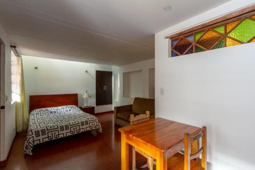 a bedroom with a bed and a table and a window at Apartaestudios La Candelaria in Bogotá