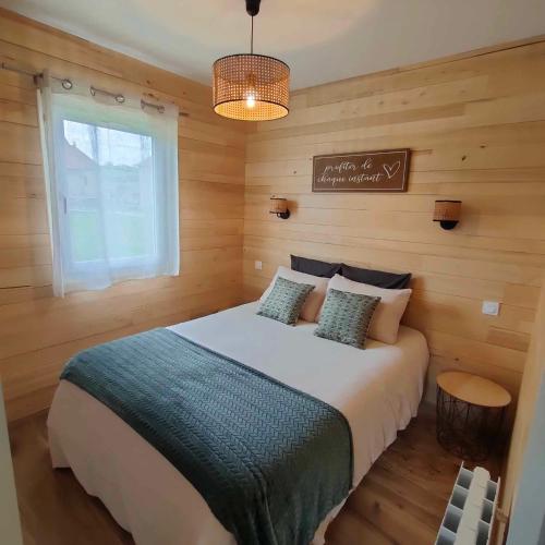 a bedroom with a large bed with wooden walls and a window at Gîte, aux portes du Morvan in Voudenay-lʼEglise