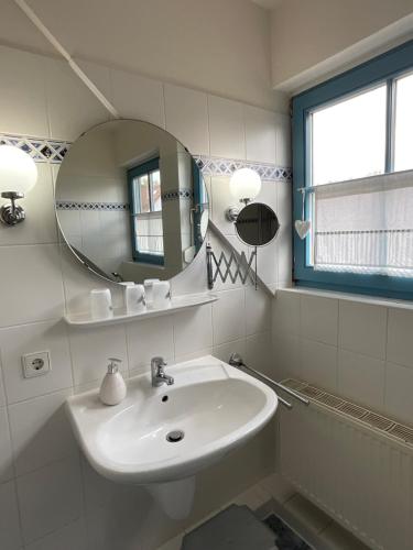 a white bathroom with a sink and a mirror at Schwalbennest in Zingst