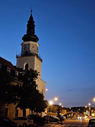 a tall building with a clock tower at night at Chalet Robinson in Modra