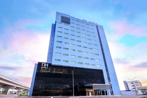 a tall white building with a sign on it at NH Puebla FINSA in Puebla