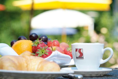 una mesa con una bandeja de fruta y una taza de café en Parkhotel Wolfsburg, en Wolfsburg
