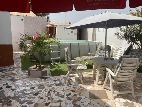 a patio with chairs and a table and an umbrella at The Compound in Bijilo