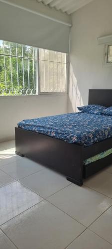 a bedroom with a bed with a blue comforter and two windows at VILLETA, CASA CAMPESTRE CERCA DE PAYANDE in Villeta
