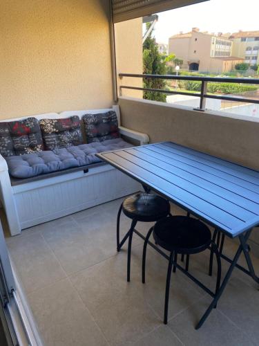 une table bleue et deux tabourets sur un balcon dans l'établissement Beverley hills, au Cap d'Agde