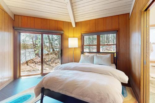 1 dormitorio con paredes de madera y 1 cama con ventana en The Octagon on Big Bass, en Eagle River