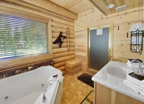 un bagno in stile baita di tronchi con vasca e lavandino di Trophy Room Retreat - Large Lodge Sleeps Up To 15 a Duck Creek Village
