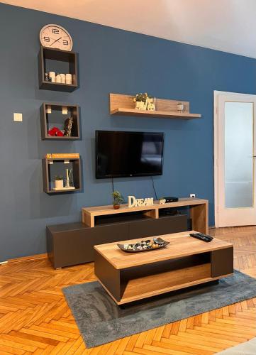 ein Wohnzimmer mit einem TV und einer blauen Wand in der Unterkunft Cozy Nest Apartment in Belgrad
